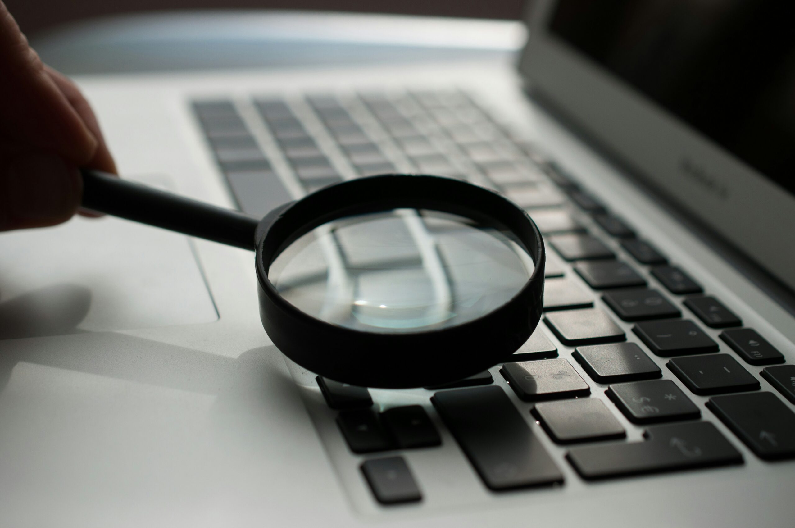 Magnifying Glass Near Gray Laptop Computer